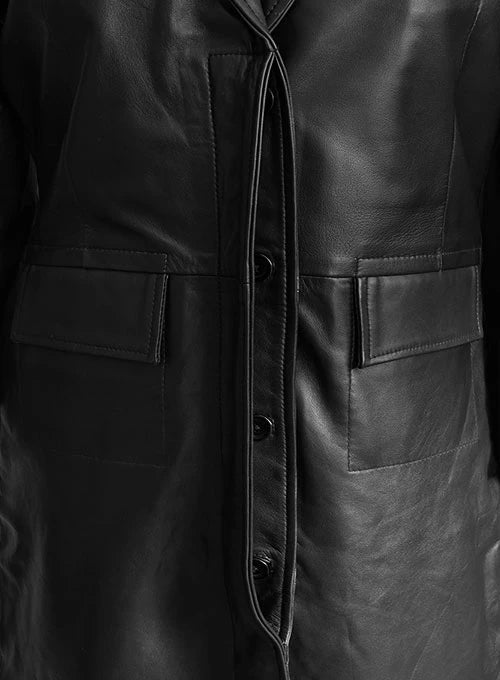 Close-up of a black leather coat with buttons and pocket details.