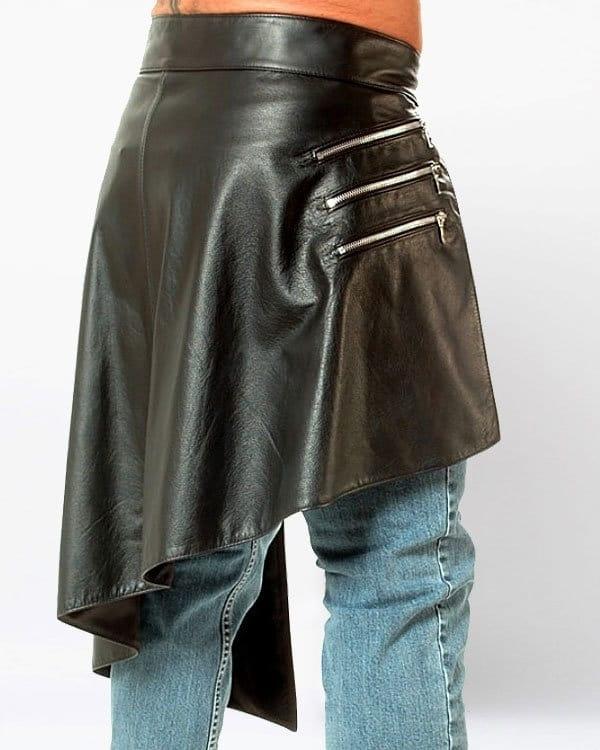 Black leather skirt with zippers worn over blue jeans on a white background