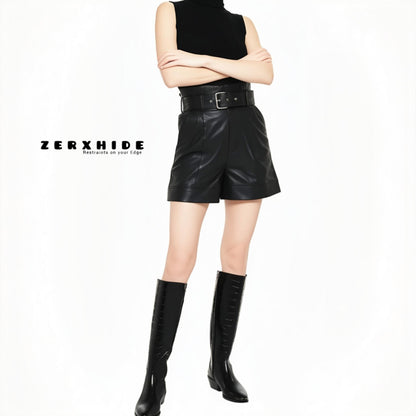 ZERXHIDE black leatherette shorts lifestyle — high-waisted belted shorts with cuffed hem styled with boots and turtleneck